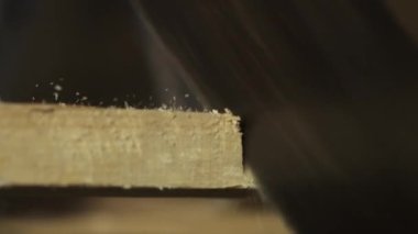 Marangozluk ve el işi reklam konsepti. Garajda çalışan erkek marangoz. Profesyonel marangoz, atölyede ahşap malzemelerle çalışıyor. Elle testereyle odun kesiyor, yakın çekim yapıyor..