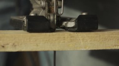 Marangozluk ve el işi reklam konsepti. Garajda çalışan erkek marangoz. Atölyede çalışan profesyonel marangoz. Tahtayı testereyle kesen elektrikli yapbozu yakından çek..