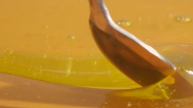 Yemek reklamı konsepti. Sağlıklı organik bal. Sarı arka planda tatlı altın bal, bal kaşığıyla kalın sıvı, yakın çekim..