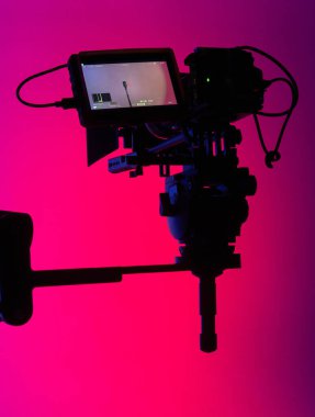 Çarpıcı bir neon arkaplanı olan bir kamera silueti, modern film üretimi için görsel bir metafor..