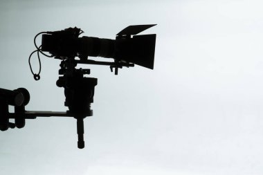 Profesyonel bir kamera ve ekipmanın parlak bir stüdyo arkaplanındaki saf silueti film yapımcılığının özünü anımsatıyor..