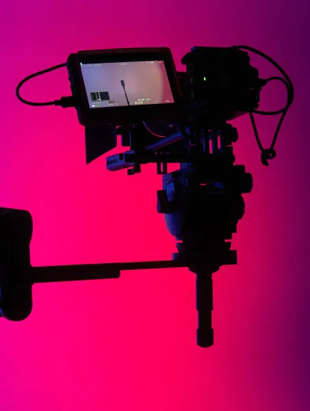 A cameras silhouette with a striking neon pink background, a visual metaphor for modern film production.