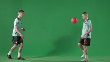 Krom anahtar yeşil ekran arka planında futbol oyuncuları. Erkek profesyonel futbolcular topla oynuyor, ayaklarıyla, başlarıyla ve dizleriyle vuruyor..