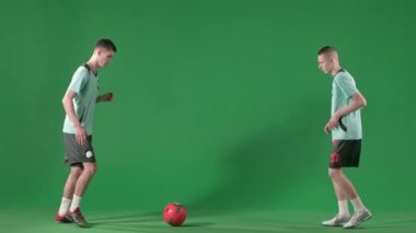 Krom anahtar yeşil ekran arka planında futbol oyuncuları. Erkek profesyonel futbolcular topla oynar, birbirlerine ayaklarıyla vururlar..