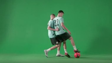 Krom anahtar yeşil ekran arka planında futbol oyuncuları. Erkek profesyonel futbolcular topla oynar, topa vurur ve kaçar..