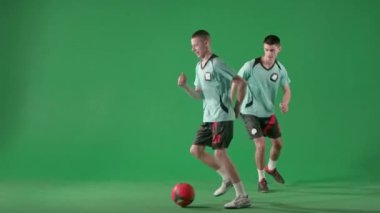 Krom anahtar yeşil ekran arka planında futbol oyuncuları. Erkek profesyonel futbolcular top oynuyorlar, topa vuruyorlar, koşuyorlar, kıvırıyorlar..