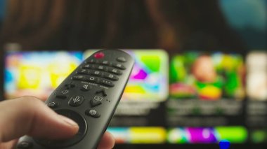 Uzaktan kumandalı kadın. Uzaktan kumandalı kanal değiştiren kadın, akıllı TV teknolojisi internet içeriği, arka planda içeriği yakın plan çekiminde olan ekran.