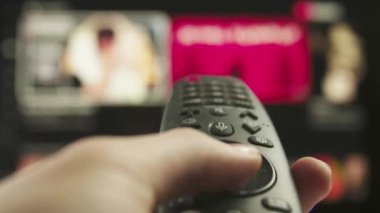 Uzaktan kumandalı kadın. Uzaktan kumandalı kanal değiştiren kadın, akıllı TV teknolojisi internet video içeriği, arka planda ortam içeriği olan ekran yakın plan çekimi.