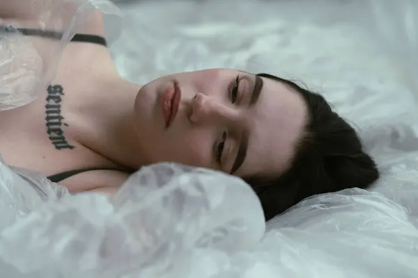 Жінка Татуюваннями Лежить Розслаблена Білому Ліжку Передаючи Спокійну Красу Стокова Картинка