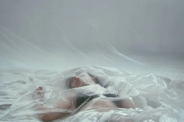 一个黑头发的年轻女子的画像 躺在半透明的床单下 看上去神思恍惚 免版税图库图片