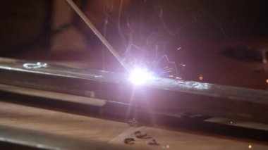 Kaynak makinesi, metal ürünler üzerinde çalışıyor. Yakın çekim. Demir yüzeyde kaynak makinesi, duman, kıvılcım ve yanıp sönen ışıklar kullanan metal işçisi, çelik kaynak yapan insan işçisi..