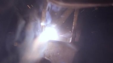 Kaynak makinesi, metal ürünler üzerinde çalışıyor. Yakın çekim. Demir yüzeyde kaynak makinesi, duman, kıvılcım ve yanıp sönen ışıklar kullanan metal işçisi, çelik kaynak yapan insan işçisi..