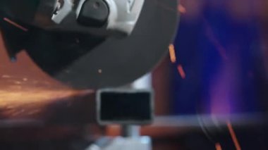 İşçi, çeliği kesmek için öğütücü makine kullanıyor. Koruyucu eldivenler giymiş bir zanaatkar fabrikada öğütücüyle çalışıyor demir parçaları öğüten bir adam, etrafta uçuşan kıvılcımlar, cam levha manzarası..