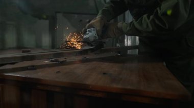 Çelik boru kesmek için öğütücü kullanan bir işçi. Koruyucu eldivenler giymiş bir zanaatkar ve endüstriyel fabrikada öğütücüyle çalışıyor..
