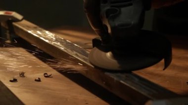 İşçi, çeliği kesmek için öğütücü makine kullanıyor. Koruyucu eldivenler giymiş bir zanaatkar endüstriyel fabrikada öğütücüyle çalışıyor demir parçaları öğütüyor, kamerada kıvılcımlar uçuşuyor..