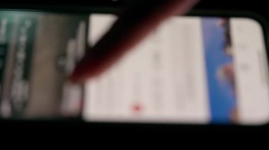 Düşük ışıkta akıllı telefon ekranındaki bir videoda, dokunmatik ekranla etkileşimi vurgulayan bir parmağın yakın plan görüntüsü.