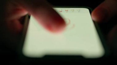 Düşük ışıkta bir akıllı telefon ekranında, dokunmatik ekranla etkileşimi vurgulayan bir parmak resmi.
