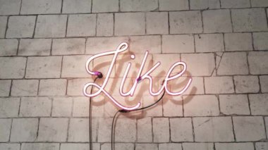 Pembe neon gibi bej tuğla bir duvarda parlayan bir tabela, şık ve modern bir sosyal medya yaratıyor..