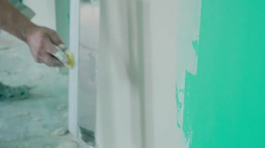 Duvarın yenilenmesi ve hazırlanması ile ilgili kesin çalışmaları gösteren bir mala kullanarak duvara macun uygulayan bir elin yakın plan görüntüsü. DIY ve inşaat temaları için ideal.