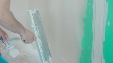 Duvarın yenilenmesi ve hazırlanması ile ilgili kesin çalışmaları gösteren bir mala kullanarak duvara macun uygulayan bir elin yakın plan görüntüsü. DIY ve inşaat temaları için ideal.