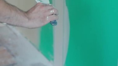Duvarın yenilenmesi ve hazırlanması ile ilgili kesin çalışmaları gösteren bir mala kullanarak duvara macun uygulayan bir elin yakın plan görüntüsü. DIY ve inşaat temaları için ideal.