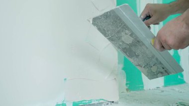 Bir inşaat işçisi macunu duvara sürmeden önce malaya yerleştirir. Bu yakın plan resim, pürüzsüz bir bitiş için gereken detayı ve hassasiyeti gösterir..