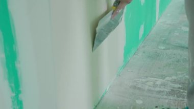 Duvarın yenilenmesi ve hazırlanması ile ilgili kesin çalışmaları gösteren bir mala kullanarak duvara macun uygulayan bir elin yakın plan görüntüsü. DIY ve inşaat temaları için ideal. Yavaş çekim