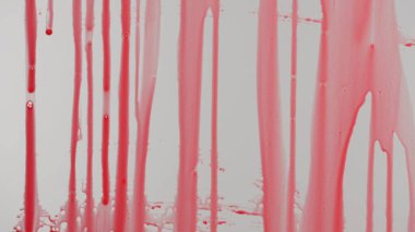 Cam bir yüzeyden damlayan kırmızı boyanın yakın plan görüntüsü soyut bir desen oluşturuyor. Kırmızı boya ve temiz cam arasındaki zıtlık dramatik bir etki yaratıyor..
