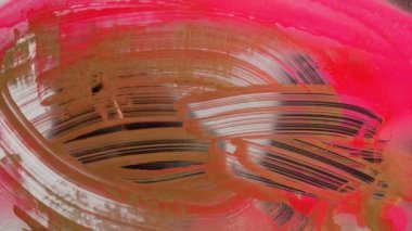 Tanınmayan bir adam cam yüzeydeki boyaları siliyor. Altın ve neon boya lekeleri bir bez parçasıyla silinir..