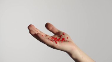 Kırmızı boyalı bir kalem beyaz arka plana düşer. Kırmızı boya çarpıcı bir karşıtlık yaratır. Derinin detaylarını ve dokusunu vurgular..