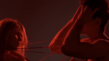 Genç erkek ve kadın aşıklar vurulur, tutku mahremiyeti, çift birbirine dolanmış vücutları iplikle bağlar, etkileyici bir ifade. Aşk ve sevgi ilişkileri kavramı. Sevgili çift stüdyoda yakın çekim yapıyor..