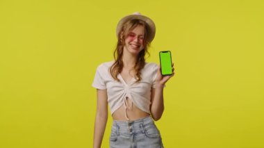 Gündelik akıllı telefon kroma anahtar yeşil ekranlı genç bir kadın. Seyahat, yaz tatili, turizm boş zaman konsepti. Sarı arka planda izole edilmiş kameraya poz veren oyuncu genç bayan model..