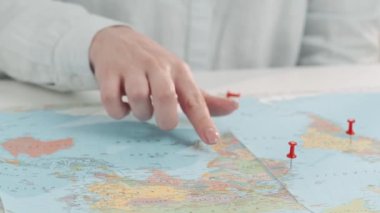 Dünya haritasındaki yerleri işaretleyen bir kadın seyahat acentesinin yakın çekimleri. Tatil planlama, seyahat için bir ülke seçme, turne rezervasyonu, biletler ve oteller.