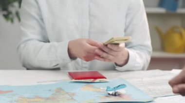 Anlaşma için para alan bir kadının ellerine yakın çekim. Seyahat acentesi parayı sayar, müşteriye biletli bir pasaport verir ve el sıkışır. Tur rezervasyonu için işlem yapıyor..