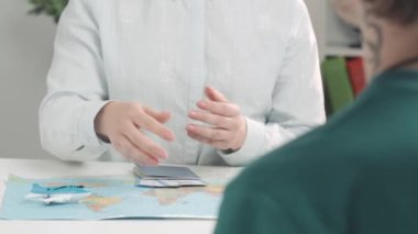 Anlaşma için para alan bir kadının ellerine yakın çekim. Seyahat acentesi parayı sayar, müşteriye biletli bir pasaport verir ve el sıkışır. Tur rezervasyonu için işlem yapıyor..