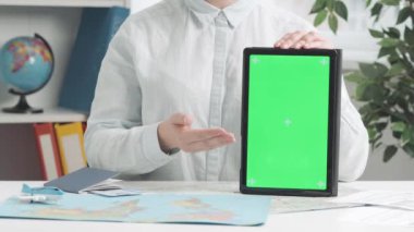 Bir seyahat acentesi elinde yeşil ekranlı bir tablet tutarak ekranı işaret ediyor ve işaret veriyor. Metin veya resim için şablon yeri, promosyon içeriği. Reklam alanı, çalışma alanı maketi.