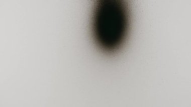 Cam bir yüzeye siyah aerosol boya ile soyut şekiller çizen bir el.