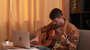 Evde gitar çalan genç bir müzisyen. Yetişkin bir gitarist odada oturmuş akustik gitar çalıyor. İnternette dizüstü bilgisayar öğrenme dersleri alıyor. Hobi ve boş zaman kavramı.
