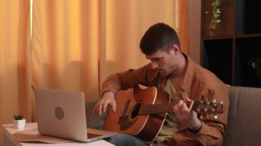 Evde gitar çalan genç bir müzisyen. Yetişkin bir gitarist odada oturmuş akustik gitar çalıyor. İnternette dizüstü bilgisayar öğrenme dersleri alıyor. Hobi ve boş zaman kavramı.