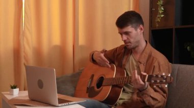 Evinde gitar çalan genç bir müzisyen. Yetişkin bir erkek gitarist bir odada oturur ve sosyal medya için dizüstü bilgisayarda video kaydederken akustik gitar çalar.