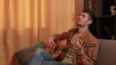 Evde gitar çalan genç bir müzisyen. Yetişkin bir gitarist odada oturup akustik gitar çalar, melodi besteler, akorları çalar, düşünür. Hobi ve boş zaman kavramı.