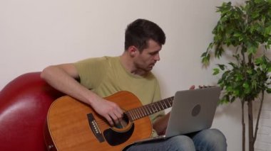 Evde gitar çalan genç bir müzisyen. Yetişkin bir gitarist odada oturmuş akustik gitar çalıyor. İnternette dizüstü bilgisayar öğrenme dersleri alıyor. Hobi ve boş zaman kavramı.