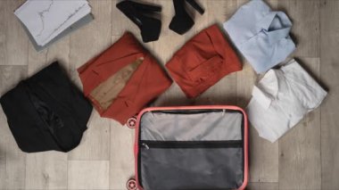 Animasyonu durdurun. İş kadını kıyafetleriyle dolu mor bavul. İş gezisi için ahşap zemin, üst manzara..