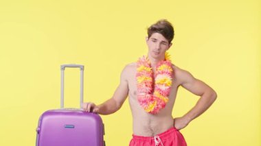 Bavulun başında bekleyen yorgun ve üzgün genç bir adam. Pembe şortlu çıplak bir adam ve sarı arka planda Hawaii lei pozu veren bir adam. Seyahat, yaz tatili.