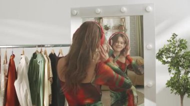 Evde aynanın önünde poz veren genç bir kadın model. Genç milenyum kadını yatak odasında aynaya bakar, kulaklıkla dans eder şarkı söyler. Kişisel bakım sağlıklı güzellik konsepti.