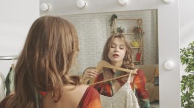 Evinde aynanın önünde poz veren genç bir kadın model. Genç bir kadın milenyumu yatak odasında aynaya bakıyor ve bir kıyafet seçiyor. Sağlıklı güzellik ve özgüven kavramı.