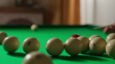 Hobi ve eğlence konsepti. Lüks bilardo kulübü sahnesi. Rus bilardo masasının kırmızı top tarafından vurulan beyaz toplarla yakın plan fotoğrafı, kibrit oynayan kişi.
