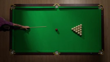 Hobi ve eğlence konsepti. Lüks bilardo kulübü sahnesi. Rus bilardo masasının tam görüntüsü kırmızı topa vurulan beyaz toplar, top piramidine bilardo sopasıyla vuran kişi..