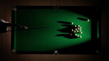 Hobi ve eğlence konsepti. Lüks bilardo kulübü sahnesi. Rus bilardo masasının tam görüntüsü kırmızı topa vurulan beyaz toplar, top piramidine bilardo sopasıyla vuran kişi..