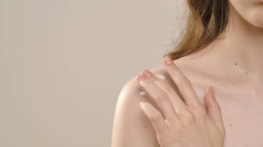 Çekici kadın model kameraya güzellik tedavisi yapıyor. Kameraya poz veren genç bir kadın, beyaz arka planda izole edilmiş, pürüzsüz tenine dokunuyor. Doğal güzellik ve cilt bakımı kavramı